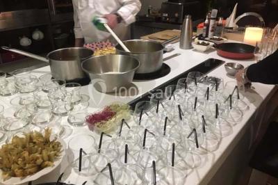Table décorée pour un dîner, avec nappes blanches, serviettes pliées, lanternes, fleurs et couverts disposés.