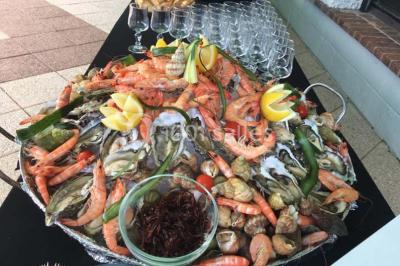 Table décorée pour un dîner, avec nappes blanches, serviettes pliées, lanternes, fleurs et couverts disposés.