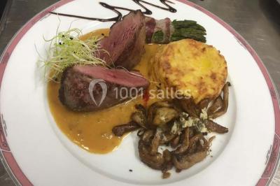Table décorée pour un dîner, avec nappes blanches, serviettes pliées, lanternes, fleurs et couverts disposés.
