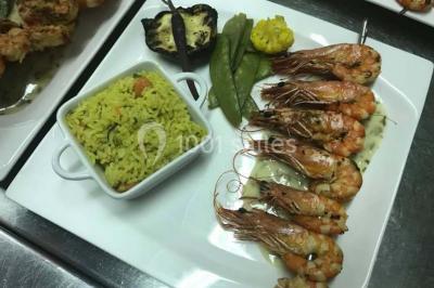 Table décorée pour un dîner, avec nappes blanches, serviettes pliées, lanternes, fleurs et couverts disposés.