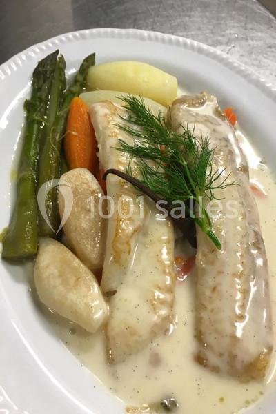 Assiette de poisson blanc nappé de sauce, accompagné d'asperges, carottes, pommes de terre et herbes fraîches.