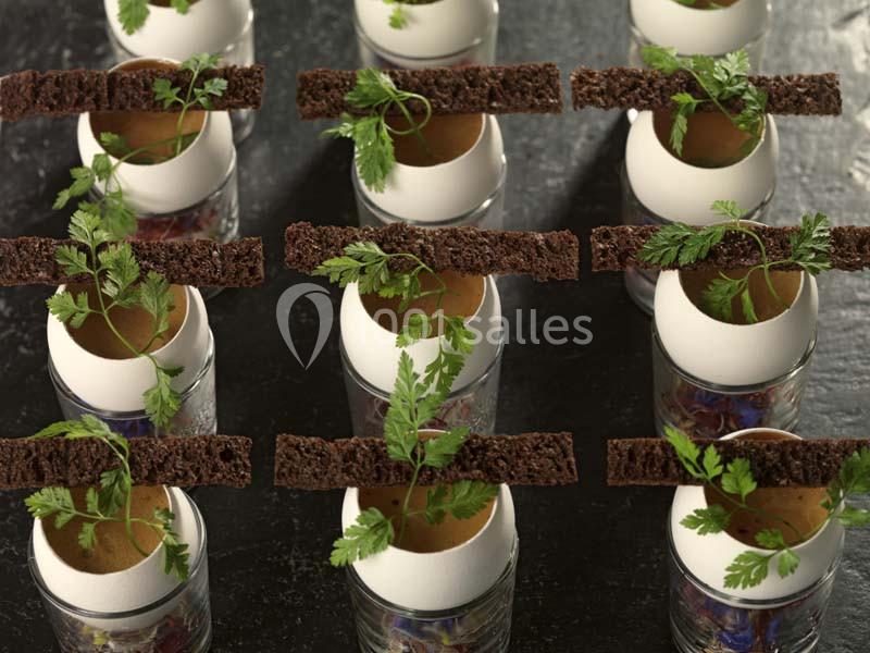 Coquilles d'œufs garnies de mousse verte, surmontées de pain croustillant et décorées de feuilles de cerfeuil.