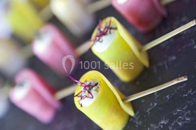 Gros plan sur un macaron rouge garni de crème blanche, posé sur une surface sombre.