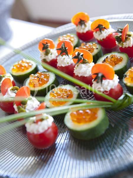 Assortiment de bouchées apéritives avec tomates, concombres, fromage frais et œufs de poisson sur un plateau.