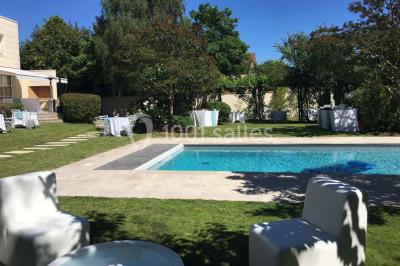 Gros plan sur un macaron rouge garni de crème blanche, posé sur une surface sombre.