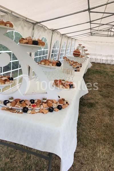 Buffet de pâtisseries et viennoiseries disposé sur des tables sous une tente blanche, en extérieur.