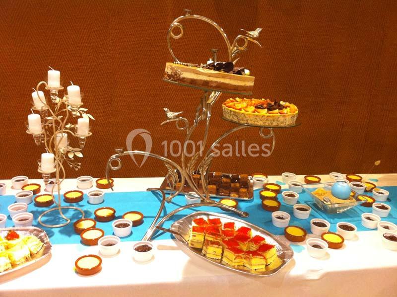 Table de buffet avec des desserts variés, dont gâteaux, tartes et verrines, présentés sur des supports décoratifs.