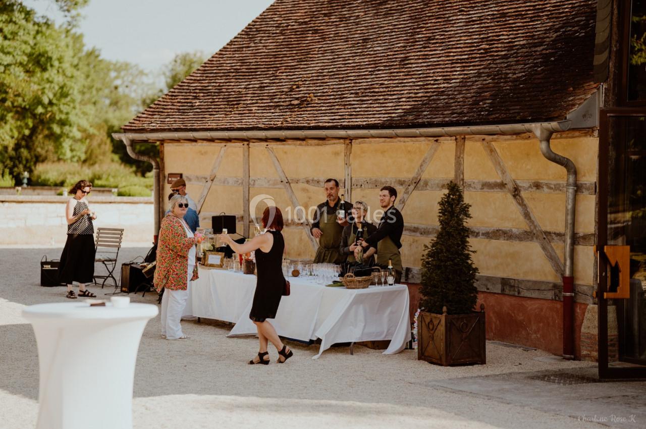 Un groupe de personnes près d'une table de buffet en extérieur, devant un bâtiment à colombages.