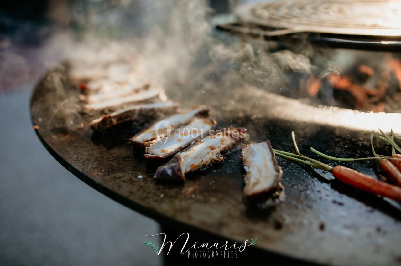 Tranches de viande grillées sur une plaque de cuisson avec des légumes, entourées de vapeur.