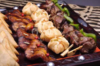 Un couple coupe un gâteau de mariage entouré de desserts décorés et de cierges magiques allumés.