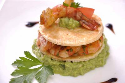 Un couple coupe un gâteau de mariage entouré de desserts décorés et de cierges magiques allumés.