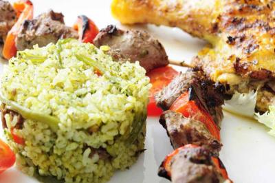 Un couple coupe un gâteau de mariage entouré de desserts décorés et de cierges magiques allumés.