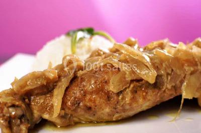 Un couple coupe un gâteau de mariage entouré de desserts décorés et de cierges magiques allumés.