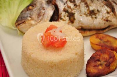 Un couple coupe un gâteau de mariage entouré de desserts décorés et de cierges magiques allumés.