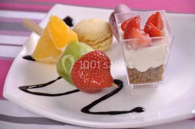 Un couple coupe un gâteau de mariage entouré de desserts décorés et de cierges magiques allumés.