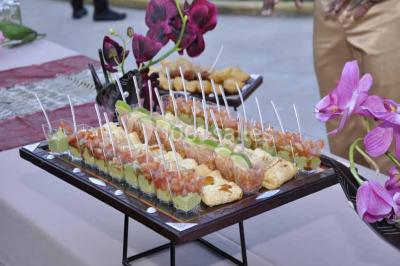 Un couple coupe un gâteau de mariage entouré de desserts décorés et de cierges magiques allumés.