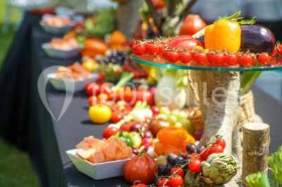 Boule croustillante sur lit de salade, garnie d'une framboise et décorée de sauce rouge sur assiette blanche.