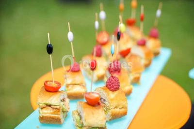 Boule croustillante sur lit de salade, garnie d'une framboise et décorée de sauce rouge sur assiette blanche.