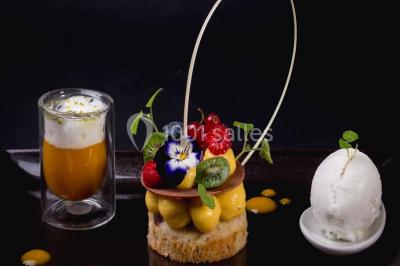 Boule croustillante sur lit de salade, garnie d'une framboise et décorée de sauce rouge sur assiette blanche.