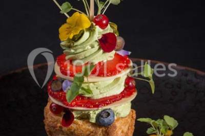 Boule croustillante sur lit de salade, garnie d'une framboise et décorée de sauce rouge sur assiette blanche.