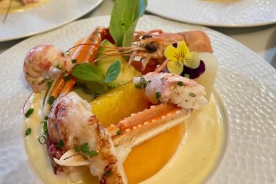 Boule croustillante sur lit de salade, garnie d'une framboise et décorée de sauce rouge sur assiette blanche.