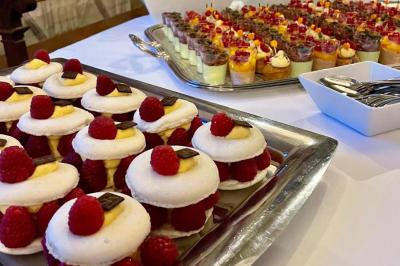 Boule croustillante sur lit de salade, garnie d'une framboise et décorée de sauce rouge sur assiette blanche.