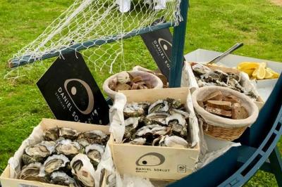 Boule croustillante sur lit de salade, garnie d'une framboise et décorée de sauce rouge sur assiette blanche.