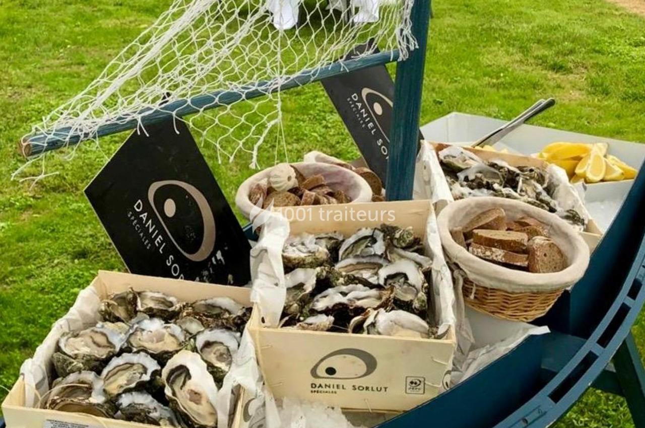 Plateau d'huîtres fraîches disposées dans des caisses en bois, accompagné de pain, citron et décoration marine.