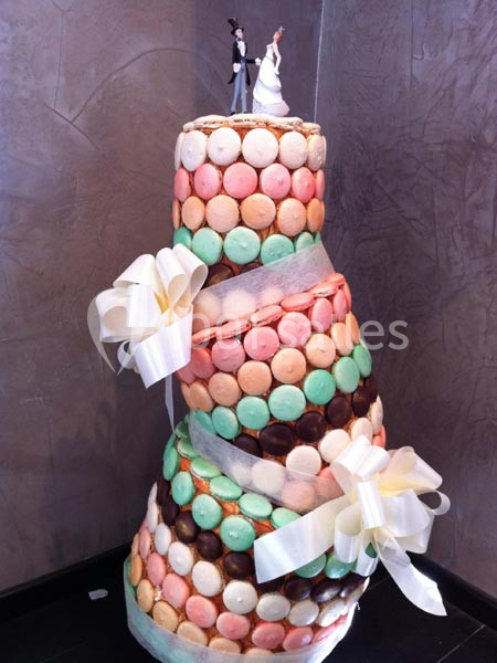 Traiteur Cloyes-les-Trois-Rivières (Eure-et-Loir) - Le Saint Jacques #6 Pièce montée inclinée décorée de macarons colorés, rubans blancs et figurines de mariés au sommet.