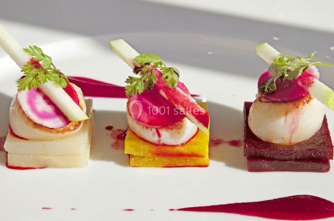 Traiteur Cloyes-les-Trois-Rivières (Eure-et-Loir) - Le Saint Jacques #9 Assiette gastronomique avec trois noix de Saint-Jacques sur des légumes colorés, décorée de fines tranches et d'herbes.