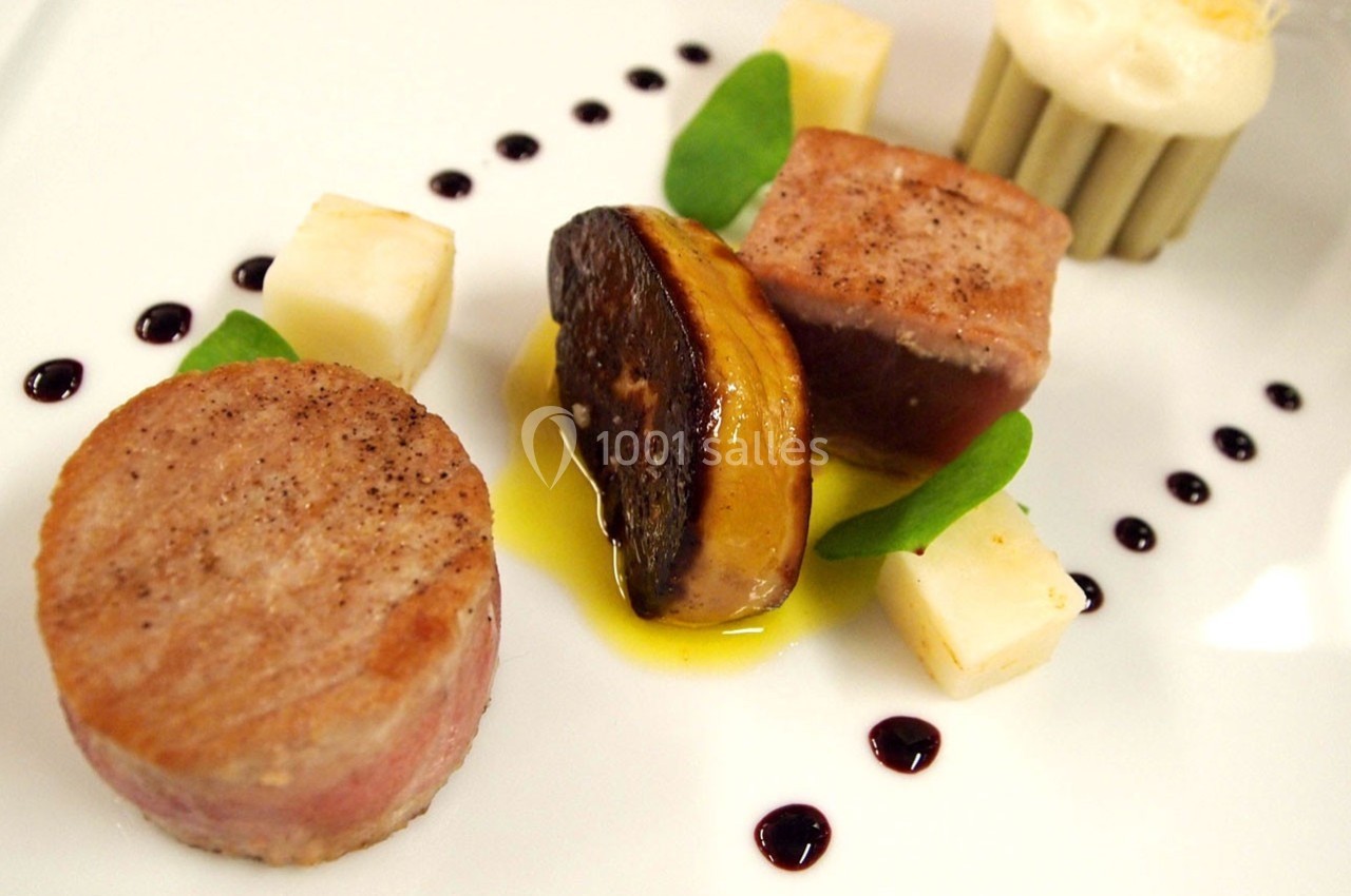 Assiette gastronomique avec viande, foie gras, cubes de fromage, sauce et décor de points de réduction balsamique.