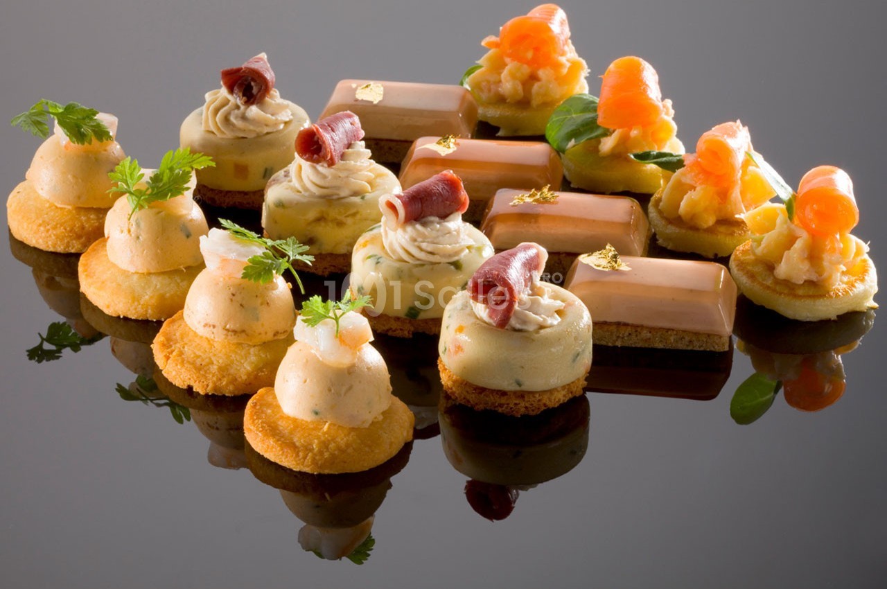 Assortiment de bouchées apéritives raffinées, comprenant mousse, saumon, jambon et décorations fines.
