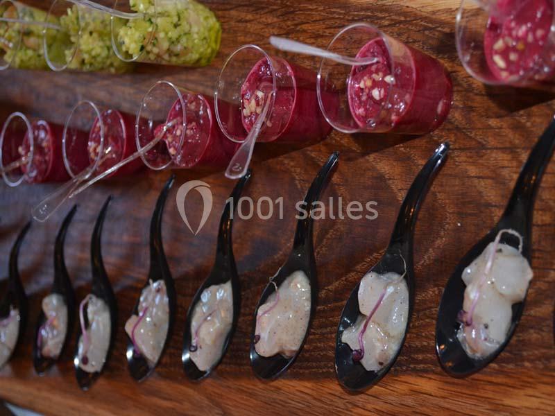 Verrines colorées et cuillères noires contenant des préparations culinaires disposées sur une table en bois.