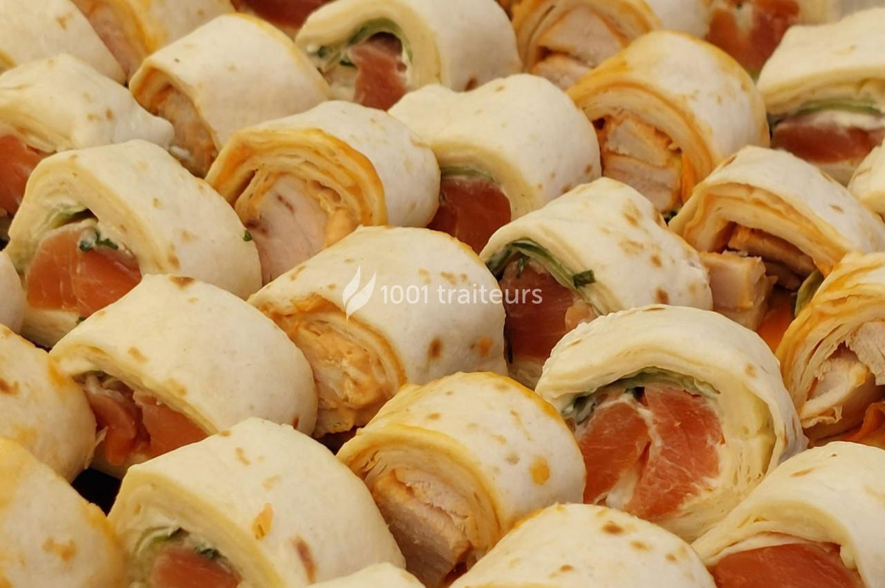 Roulés de tortillas garnis de saumon, fromage frais et herbes, présentés en rangées serrées.