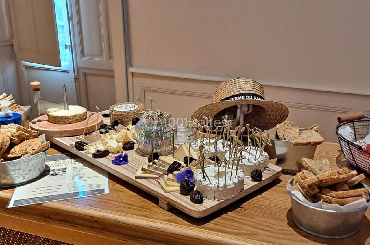 Plateau de fromages variés avec décorations, accompagné de pain et de pruneaux, présenté sur une table en bois.