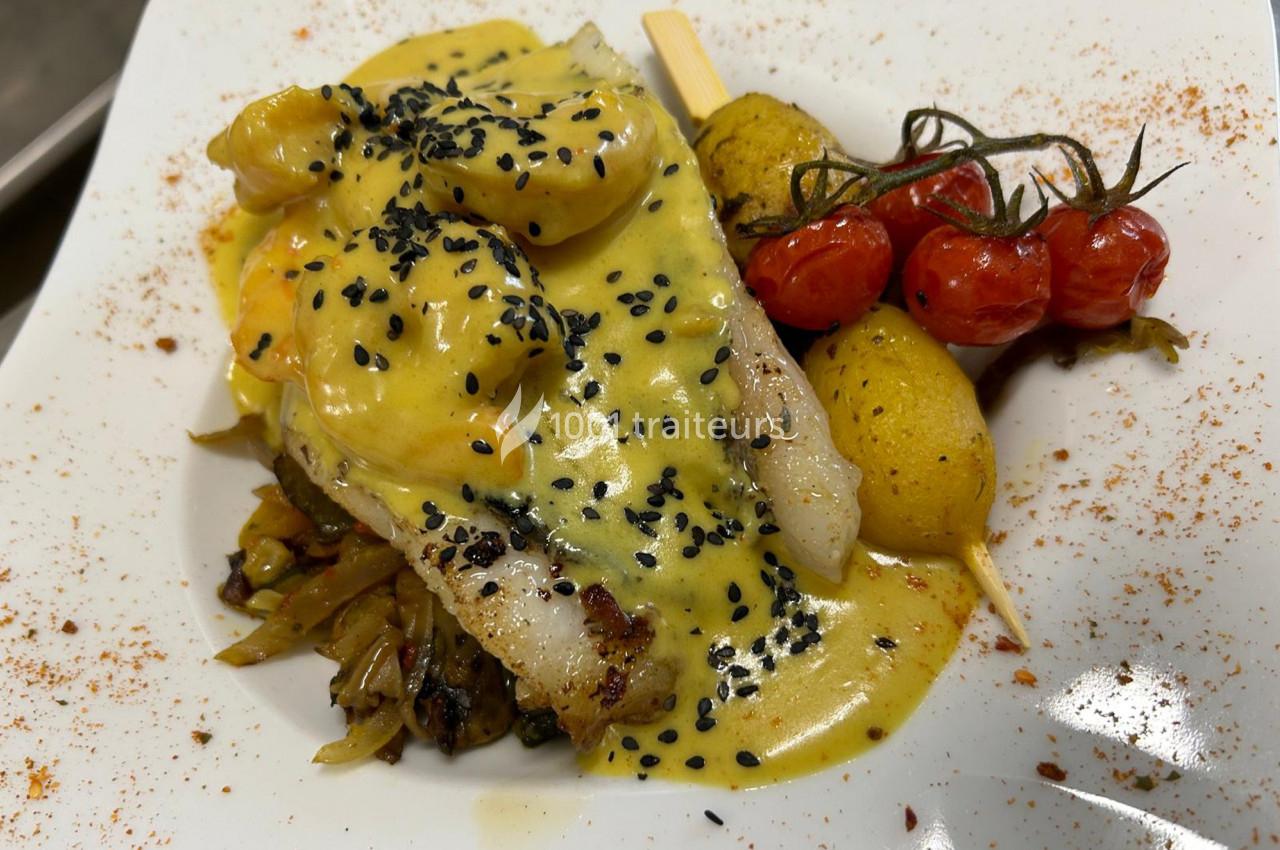 Filet de poisson nappé de sauce jaune, garni de graines noires, légumes sautés, pommes de terre et tomates cerises grillées.