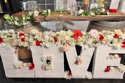 Miniature Traiteur Montauban (Tarn-et-Garonne) - Valérie Pons Traiteur #30 Décoration d'une tente événementielle avec tables ornées, barils en bois, fleurs et ballons dans un espace extérieur.