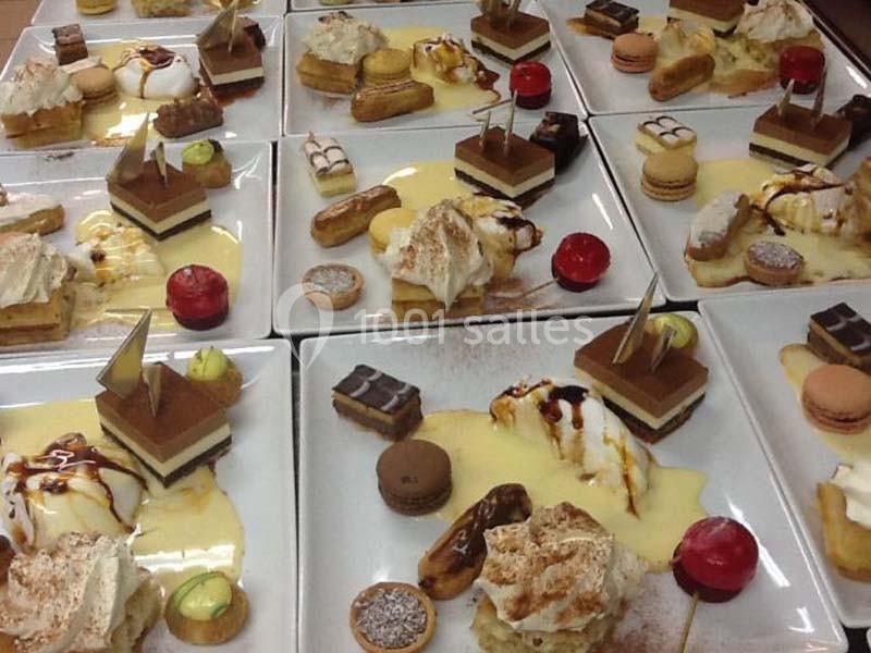 Assortiment de desserts variés présentés sur des assiettes, incluant gâteaux, macarons, éclairs et crème anglaise.