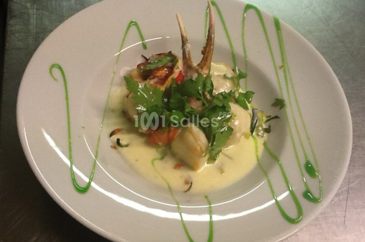 Assiette de poisson en sauce blanche, garnie de persil frais, légumes et décorée de traits de sauce verte.