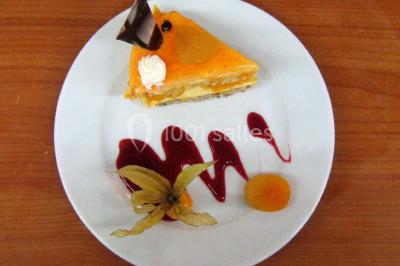 Miniature Traiteur Lezoux (Puy-de-Dôme) - Deneuville Traiteur #2 Pyramide de macarons colorés surmontée de figurines de mariés, présentée sur une table rouge en extérieur.