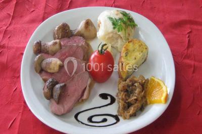 Miniature Traiteur Lezoux (Puy-de-Dôme) - Deneuville Traiteur #3 Pyramide de macarons colorés surmontée de figurines de mariés, présentée sur une table rouge en extérieur.