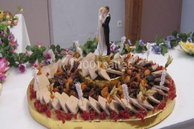 Miniature Traiteur Lezoux (Puy-de-Dôme) - Deneuville Traiteur #9 Pyramide de macarons colorés surmontée de figurines de mariés, présentée sur une table rouge en extérieur.