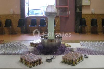 Miniature Traiteur Lezoux (Puy-de-Dôme) - Deneuville Traiteur #10 Pyramide de macarons colorés surmontée de figurines de mariés, présentée sur une table rouge en extérieur.