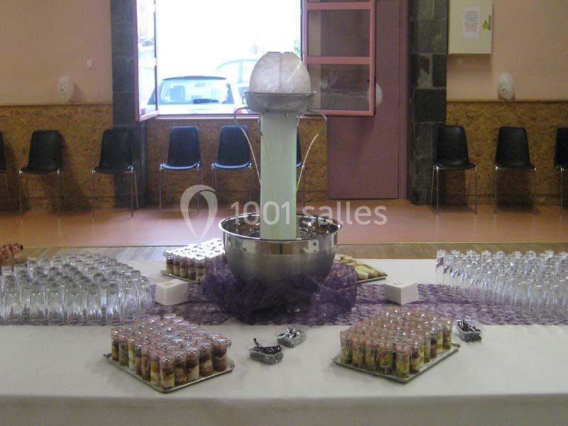 Fontaine à cocktail centrale entourée de verrines et de verres sur une table dressée dans une salle.