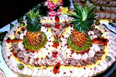 Miniature Traiteur Lezoux (Puy-de-Dôme) - Deneuville Traiteur #12 Pyramide de macarons colorés surmontée de figurines de mariés, présentée sur une table rouge en extérieur.