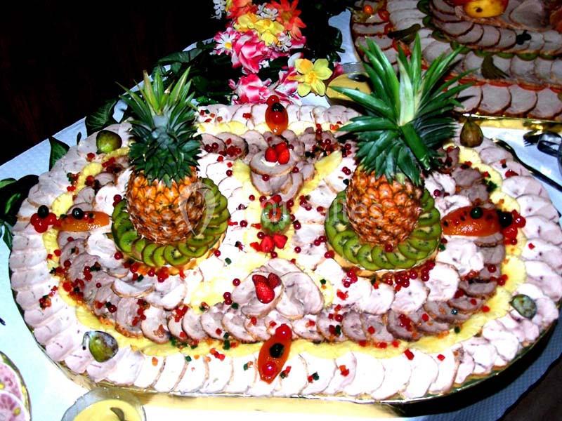 Plateau de charcuterie décoré avec des tranches de viande, fruits frais, ananas et garnitures colorées.