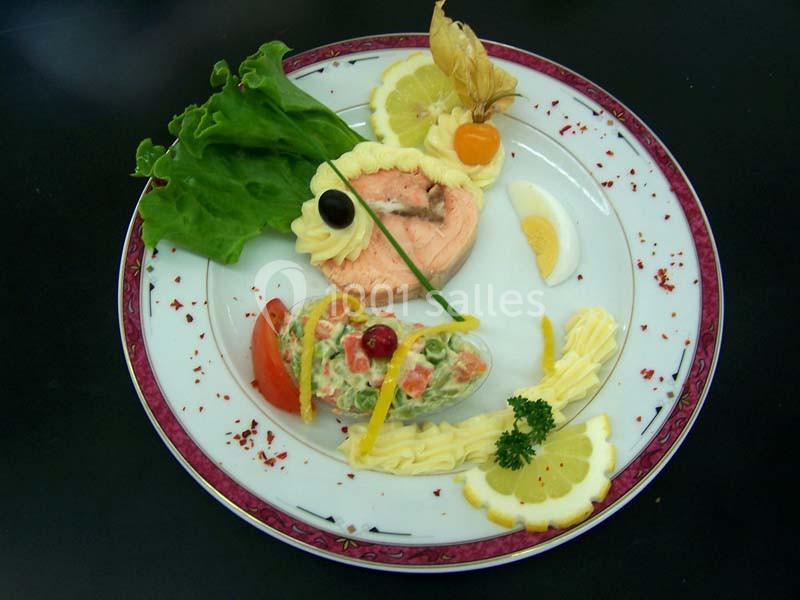 Assiette décorée avec un pavé de saumon, une salade composée, des tranches de citron et des garnitures colorées.
