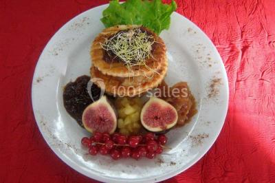 Miniature Traiteur Lezoux (Puy-de-Dôme) - Deneuville Traiteur #14 Pyramide de macarons colorés surmontée de figurines de mariés, présentée sur une table rouge en extérieur.