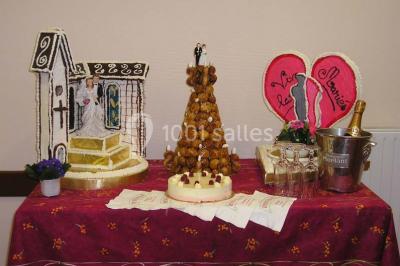 Miniature Traiteur Lezoux (Puy-de-Dôme) - Deneuville Traiteur #17 Pyramide de macarons colorés surmontée de figurines de mariés, présentée sur une table rouge en extérieur.