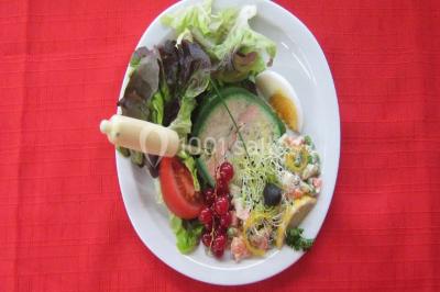 Miniature Traiteur Lezoux (Puy-de-Dôme) - Deneuville Traiteur #18 Pyramide de macarons colorés surmontée de figurines de mariés, présentée sur une table rouge en extérieur.